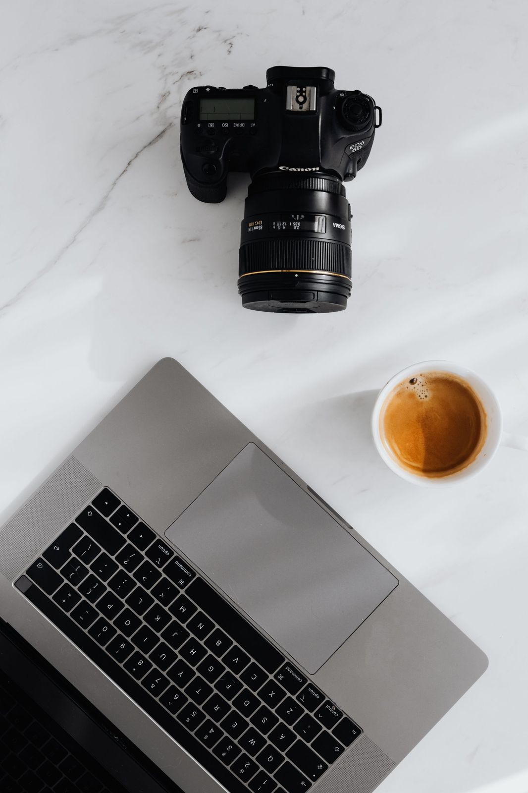 A press desk with a camera, laptop and magazines